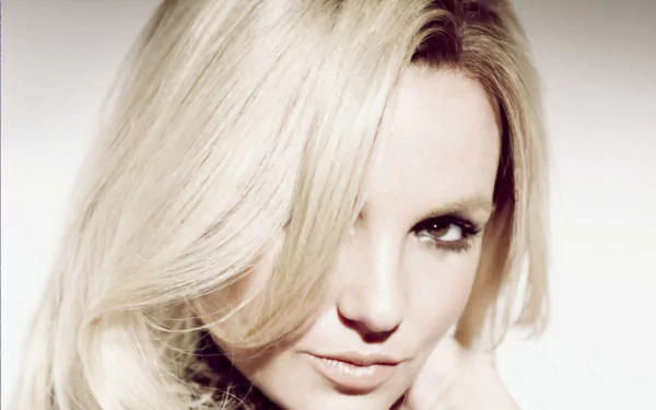 Close-up HD portrait of American singer Britney Spears with blonde hair and brown eyes, featured as a PC desktop wallpaper and background.