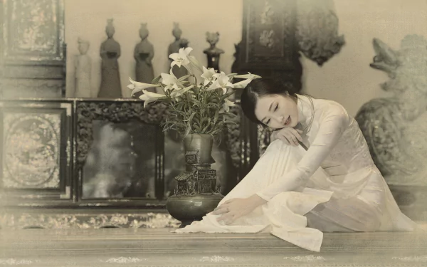 A serene Vietnamese woman in traditional Ao Dai sits gracefully beside a vase of lilies, captured in a soft sepia tone, evoking elegance and cultural beauty.