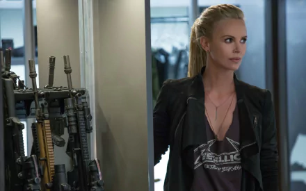Charlize Theron as Cipher in The Fate of The Furious stands confidently near an array of weapons, showcasing her character’s fierce presence in this HD wallpaper.