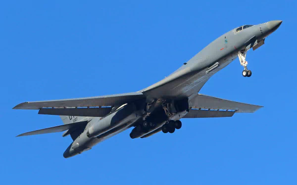 A Rockwell B-1 Lancer bomber aircraft soars against a clear blue sky, capturing the power and design of military aviation in this HD desktop wallpaper.