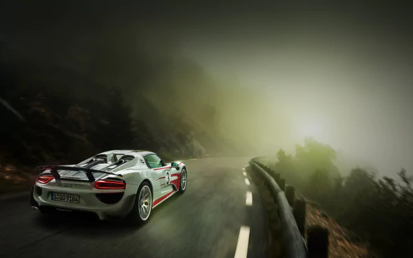 White Porsche 918 Spyder supercar driving on a misty mountain road, captured in high definition as a striking PC desktop wallpaper.