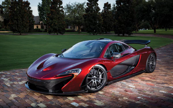 A striking McLaren P1 supercar parked on a cobblestone driveway, showcasing its sleek design and vibrant red finish against a lush green backdrop. 4K Ultra HD quality wallpaper.