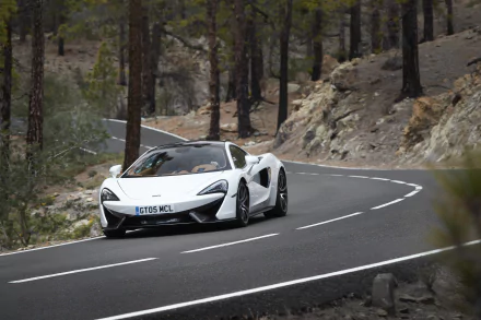 White McLaren 570GT supercar driving on a winding mountain road, captured in 4K Ultra HD as a PC desktop wallpaper and background.