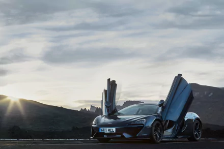 A McLaren 570GT supercar with its butterfly doors open, set against a mountainous backdrop under a cloudy sky, captured in stunning 4K Ultra HD quality.