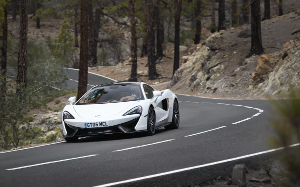 White McLaren 570GT supercar driving on a winding mountain road, captured in 4K Ultra HD as a PC desktop wallpaper and background.