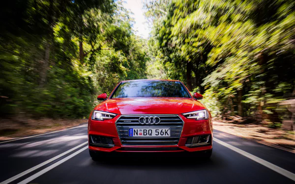 A striking red Audi A4 zooms down a scenic road, surrounded by lush greenery, creating a dynamic HD desktop wallpaper that captures the essence of performance and style.