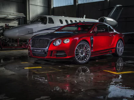 A striking red Bentley Continental GT parked in a sleek hangar, with a private jet in the background, showcasing the luxury and performance of this grand tourer vehicle.