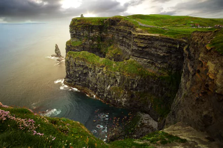 Breathtaking view of the Cliffs of Moher in Ireland, showcasing dramatic cliffs rising above the tranquil ocean amid lush greenery and a serene coastal landscape. 4K Ultra HD wallpaper quality.