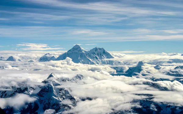 A stunning HD wallpaper of Mount Everest, towering majestically above swirling clouds, showcasing the breathtaking beauty of nature's peaks against a serene sky.