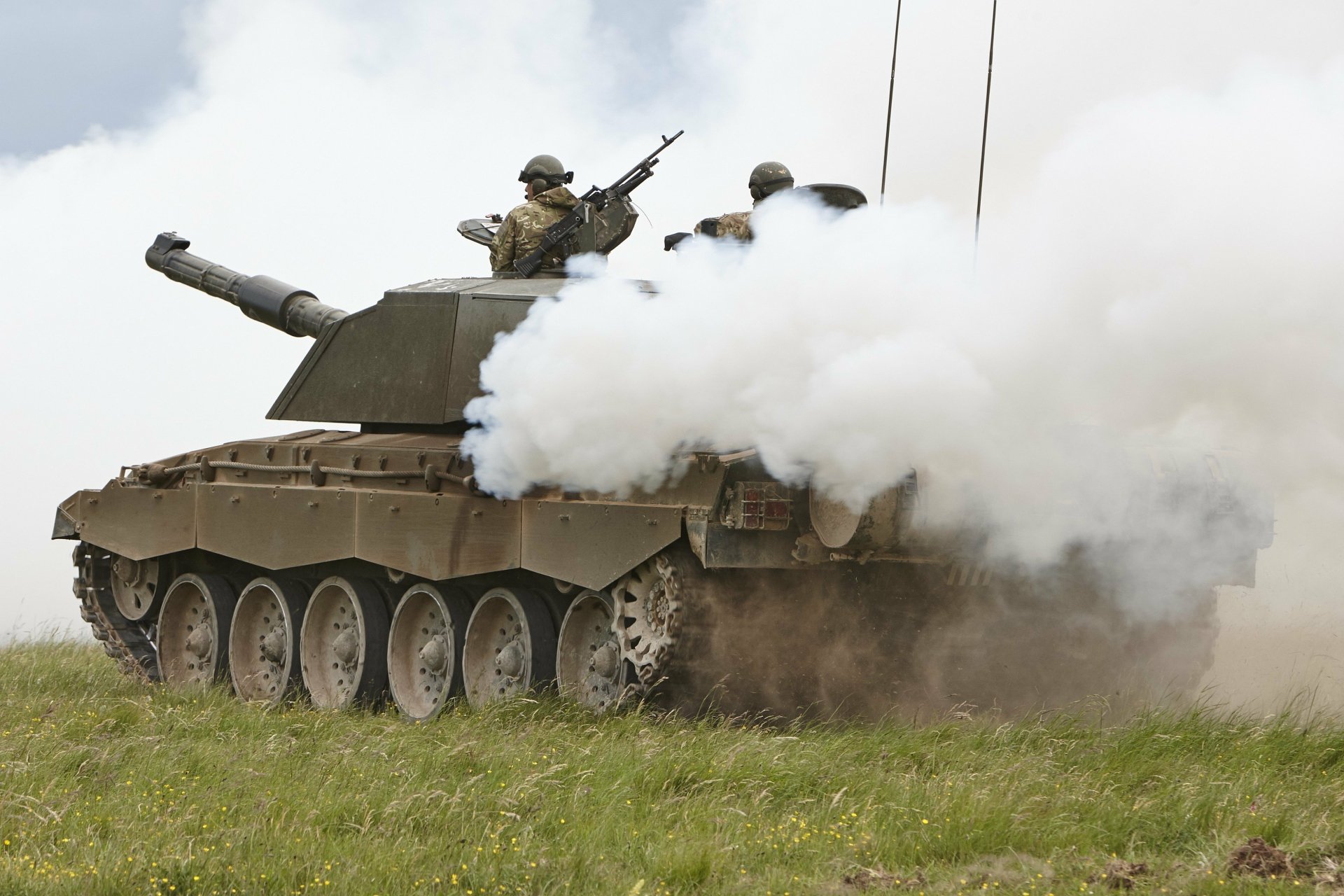 HD desktop wallpaper showing a Challenger 2 military tank emitting thick smoke with soldiers positioned on top in an open grassy field.