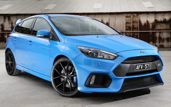 A vibrant blue Ford Focus RS compact car parked in front of a rustic industrial backdrop, captured in 4K Ultra HD for a striking PC desktop wallpaper.