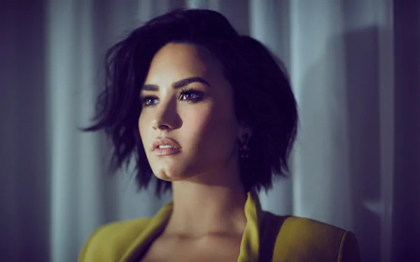 Demi Lovato, an American singer with brunette hair and brown eyes, gazes thoughtfully in this high-definition wallpaper, showcasing her captivating presence in the music scene.