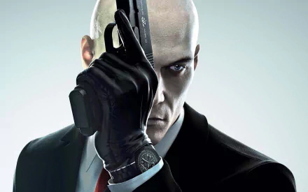 High-definition wallpaper featuring Agent 47 from the video game Hitman (2016), showcasing a close-up of him aiming a gun while dressed in a sleek suit.