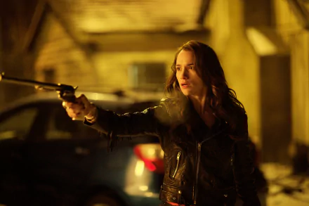 Unknown TV-series heroine fires a revolver in a dim urban alley; moody, cinematic 2K Quad HD PC desktop wallpaper and background.