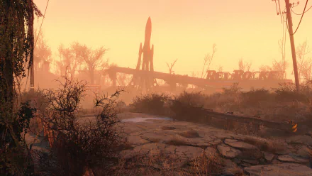A desolate landscape from Fallout 4, featuring a silhouette of a rocket against a hazy, orange sky, surrounded by remnants of a post-apocalyptic environment. HD PC desktop wallpaper.