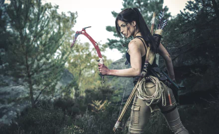 A woman in detailed Lara Croft cosplay from Tomb Raider stands confidently in a natural setting, wielding a pickaxe, capturing the adventurous spirit of Rise of the Tomb Raider.