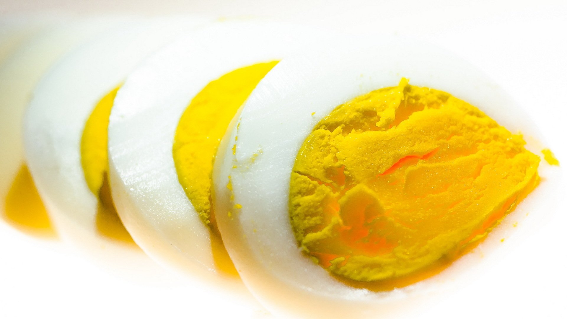 Close-up of sliced hard-boiled egg with vivid yellow yolk, HD food image used as a PC desktop wallpaper and background.