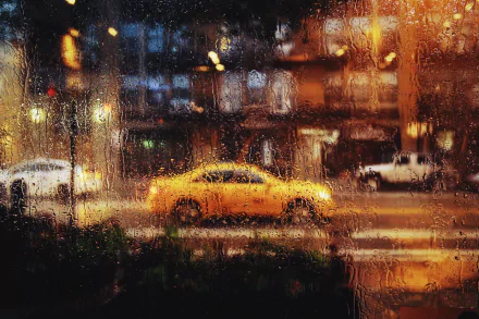 HD desktop wallpaper showing a rainy street scene through a window with raindrops, featuring blurred cars and city lights in vibrant colors.