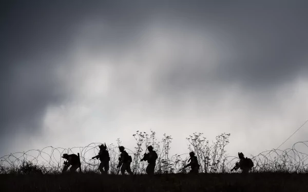 Silhouette of military soldiers walking across a hill under a cloudy sky, captured as a high-definition PC desktop wallpaper and background.