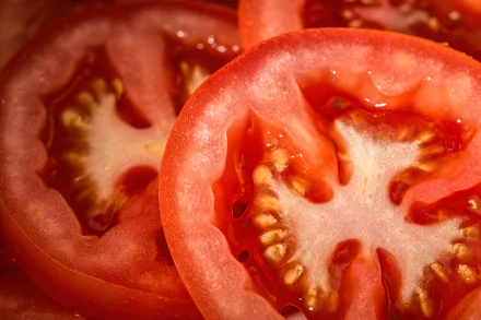 Close-up of sliced red tomato with glistening seeds and juicy flesh, a vibrant food image rendered as a 4K Ultra HD PC desktop wallpaper and background.