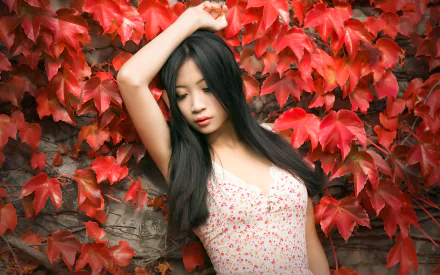 Asian woman with long black hair poses thoughtfully against a vibrant wall of red leaves, captured in stunning 4K Ultra HD for a striking desktop wallpaper.