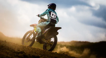 A motocross rider navigates a dirt track, kicking up dust in a dynamic action shot. The image captures the thrill of dirt biking, making it a striking HD desktop wallpaper.