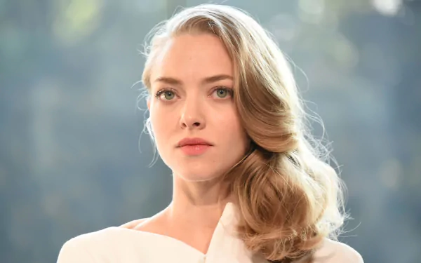 HD desktop wallpaper featuring American actress Amanda Seyfried with blonde hair and green eyes against a softly blurred background.