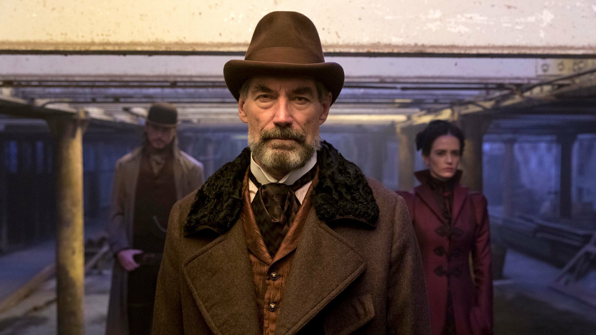 HD PC wallpaper from the TV show Penny Dreadful: a stern, hat-wearing Victorian man stands on a dim underground platform with two shadowy figures behind him.