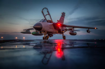 A Panavia Tornado jet fighter is captured in stunning detail, reflecting the evening lights on a wet runway, showcasing its military design and significance.