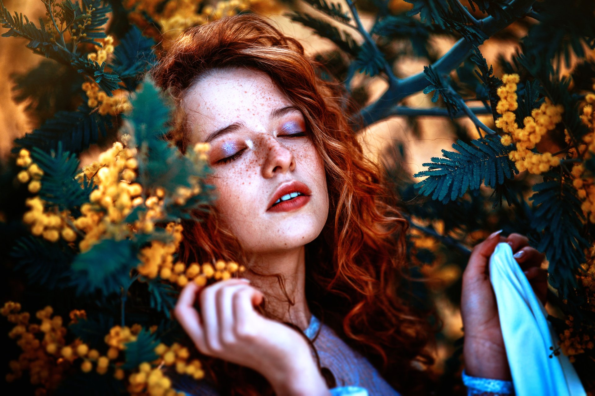 HD desktop wallpaper of a redhead woman with freckles and lipstick, surrounded by vibrant yellow flowers, capturing a serene and moody facial expression.