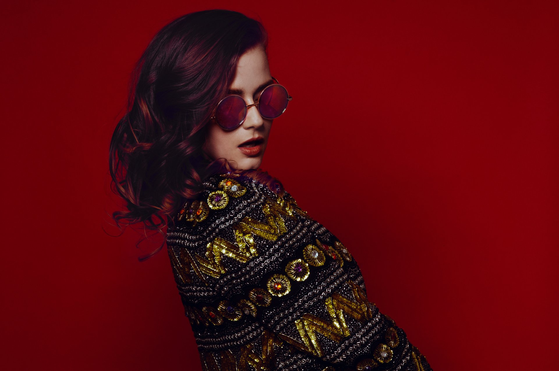Brunette woman model in round sunglasses and an ornate patterned jacket against a deep red backdrop — HD PC desktop wallpaper and background