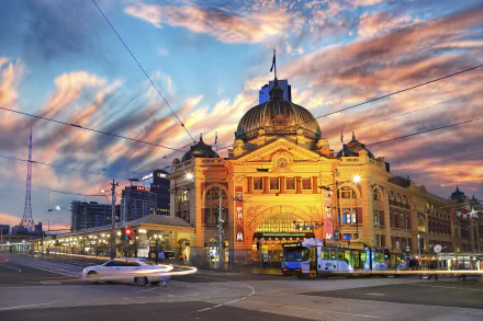A vibrant Melbourne street at dusk featuring a tram station and historic buildings, under a colorful sky, showcasing the city’s man-made beauty.