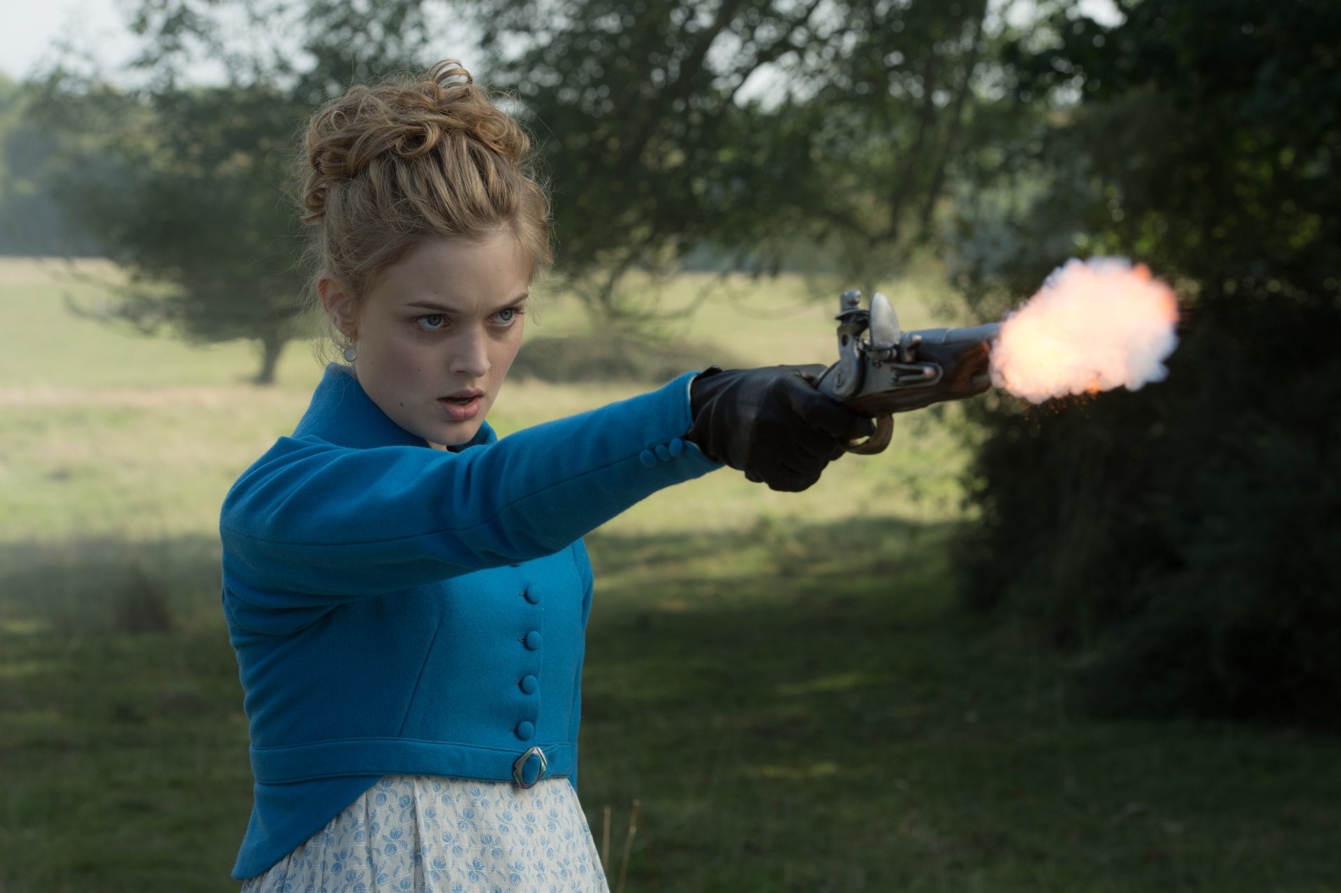 Pride and Prejudice and Zombies movie wallpaper: woman in blue Regency dress firing a pistol across a sunlit grassy field, 2K Quad HD PC desktop background.