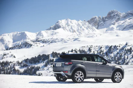 A silver Land Rover Range Rover Evoque SUV parked on snow with a backdrop of snow-covered mountains, captured in 4K Ultra HD.