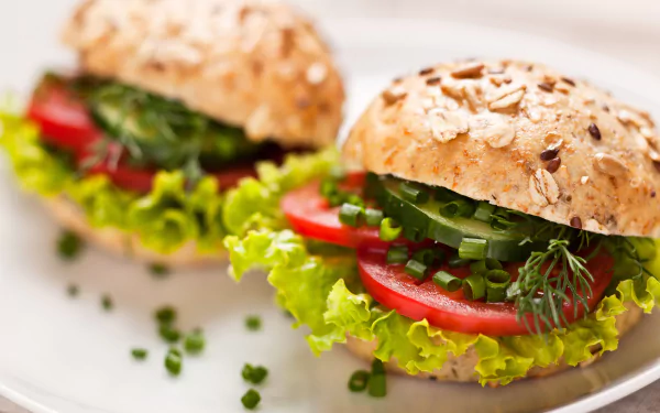Close-up of a fresh burger with cucumber, lettuce, tomato, and seeded bread, captured in 4K Ultra HD for a vibrant PC desktop wallpaper.