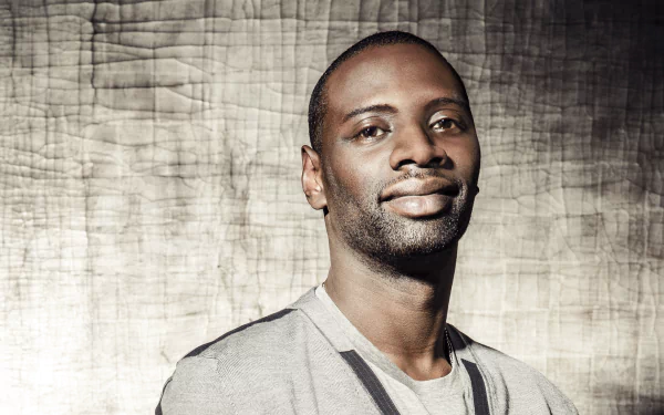 HD desktop wallpaper featuring French actor and celebrity Omar Sy against a textured background, showcasing a confident and relaxed expression.