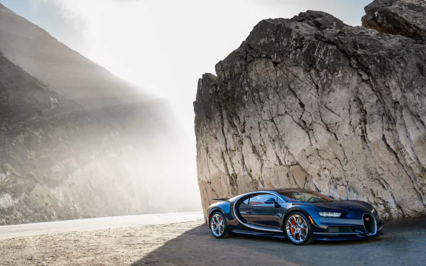 A stunning Bugatti Chiron parked against a dramatic rocky backdrop, showcasing its sleek design in a captivating 4K Ultra HD wallpaper for automotive enthusiasts.