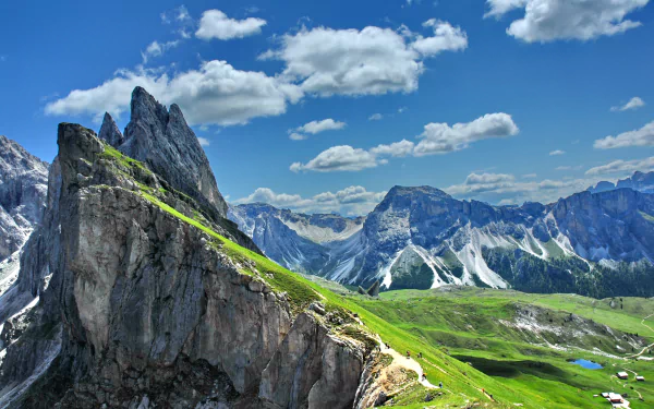 Dramatic peaks and cliffs of the Dolomites in the Italian Alps under a bright blue sky, showcasing stunning natural mountain landscape and lush green slopes.