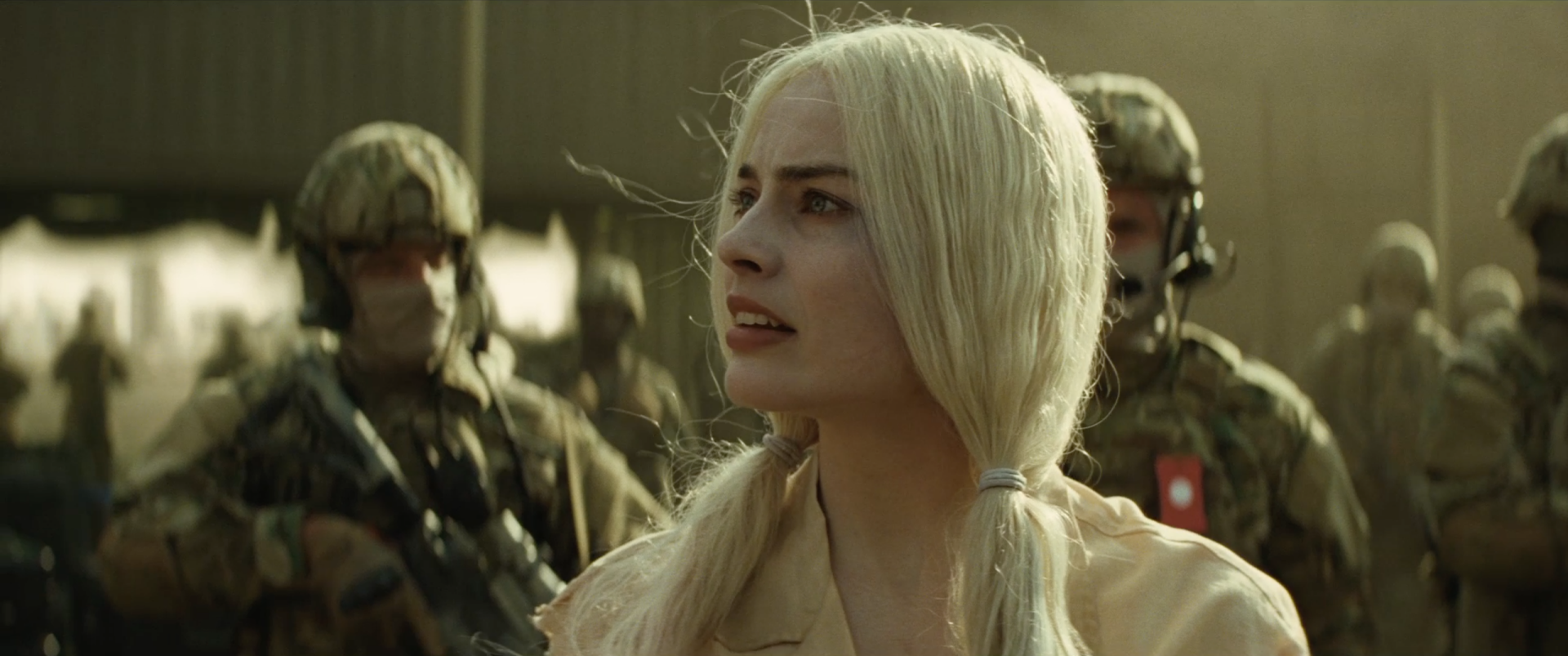 Margot Robbie as Harley Quinn in a scene from Suicide Squad, capturing her fierce expression against a backdrop of soldiers. An engaging HD desktop wallpaper.