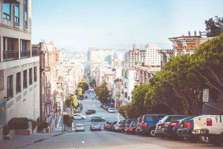 A stunning San Francisco cityscape featuring a steep street lined with houses and parked cars, showcasing the charm of urban life in this iconic USA location.