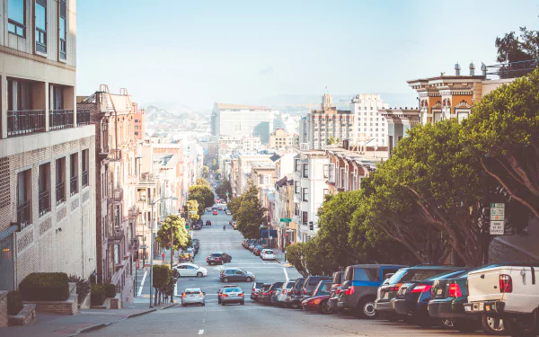 A stunning San Francisco cityscape featuring a steep street lined with houses and parked cars, showcasing the charm of urban life in this iconic USA location.