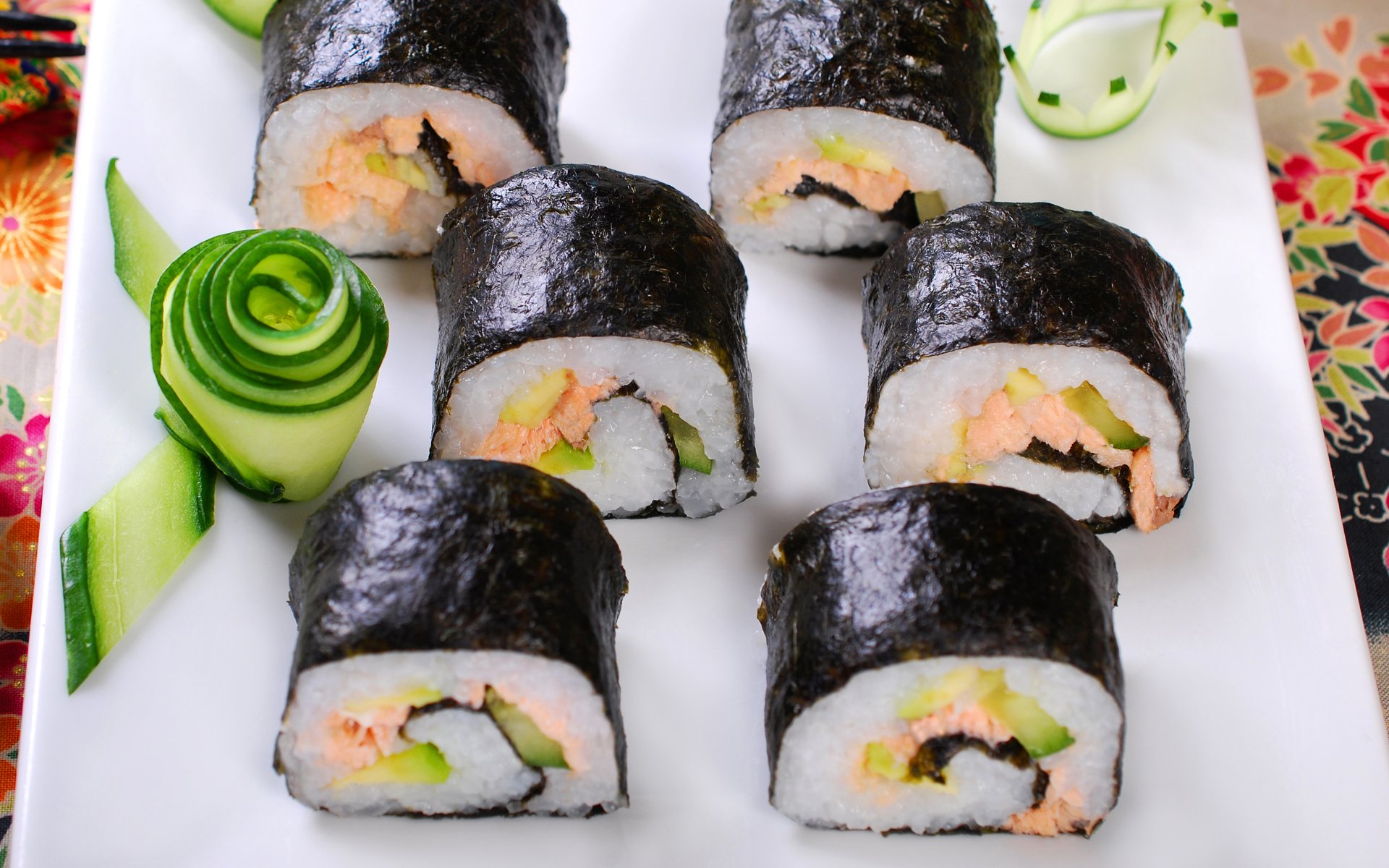 HD PC desktop wallpaper: close-up of seafood sushi rolls on a white plate with cucumber garnish, vibrant food background.