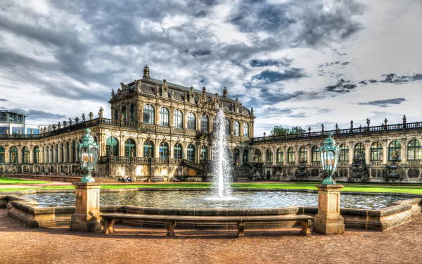 A stunning HD desktop wallpaper of the Zwinger Palace in Dresden, Germany, featuring intricate architecture and a central fountain under a dramatic sky.