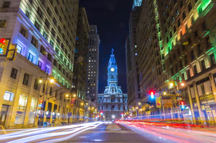 Nighttime time-lapse of Philadelphia city streets with illuminated buildings and the historic city hall in view, showcasing vibrant urban lights in the USA.