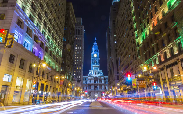 Nighttime time-lapse of Philadelphia city streets with illuminated buildings and the historic city hall in view, showcasing vibrant urban lights in the USA.