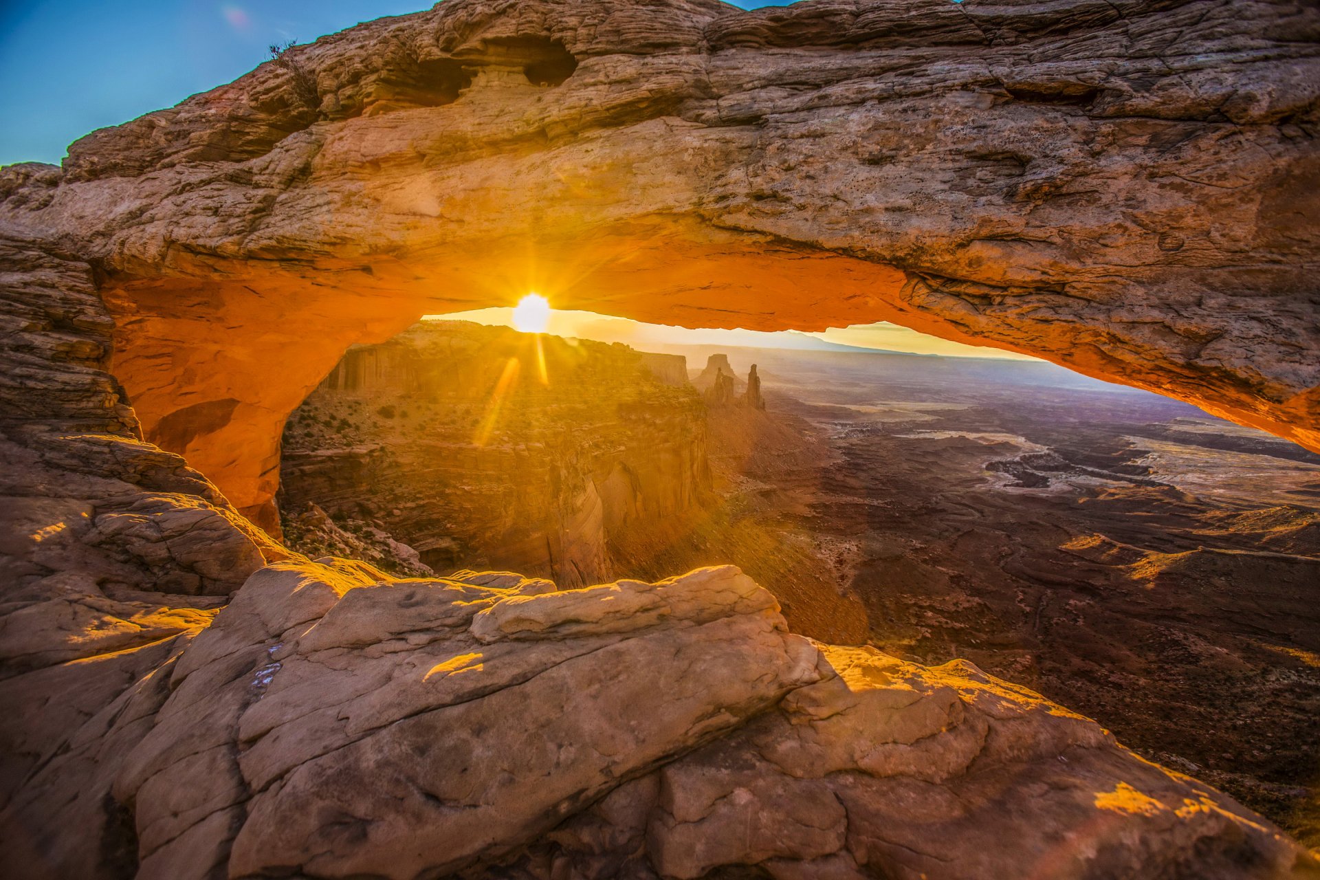 Sunbeam through Mesa Arch in a USA national park, illuminating canyon and distant mountain spires — 4K Ultra HD PC desktop wallpaper and background of dramatic nature.
