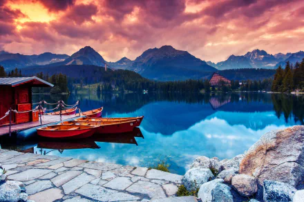 2K Quad HD PC wallpaper: sunset over a Slovak mountain lake, canoes and a boat tied to a wooden dock, mirrored peaks and a small lakeside vehicle near a chalet.