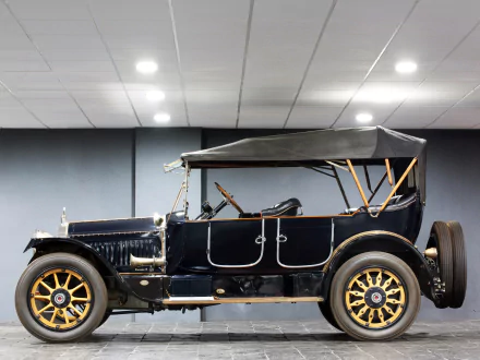 Side view of a vintage 1916 Packard Twin Six Phaeton with black body, brass-accent wheels and folded soft top, presented as an HD PC desktop wallpaper/background.
