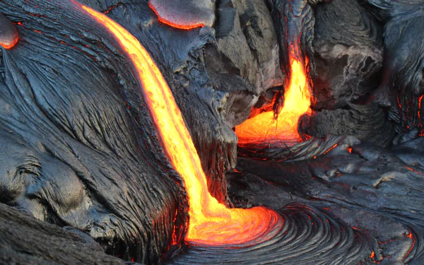 HD PC desktop wallpaper and background of a volcano: vivid lava streams glowing orange as they carve dark cooled rock in a dramatic nature scene.