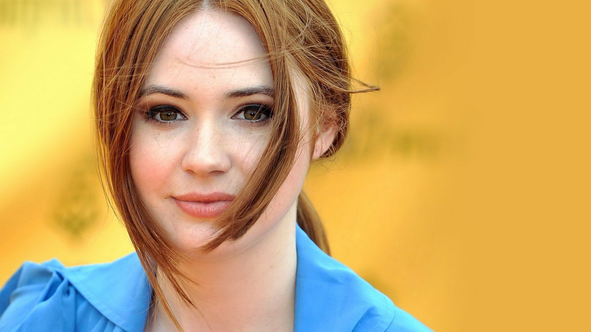 HD desktop wallpaper featuring a close-up portrait of redhead celebrity Karen Gillan against a warm, blurred yellow background.